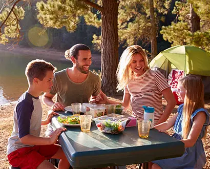 Familj äter vid picknickbord