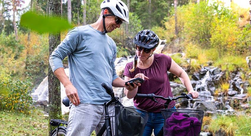 Två cyklister tittar på mobilen