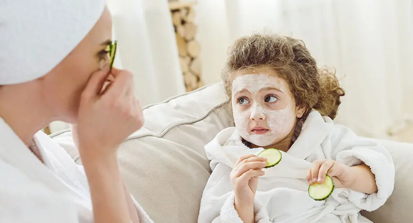Mamma och barn provar ansiktsmask med gurka