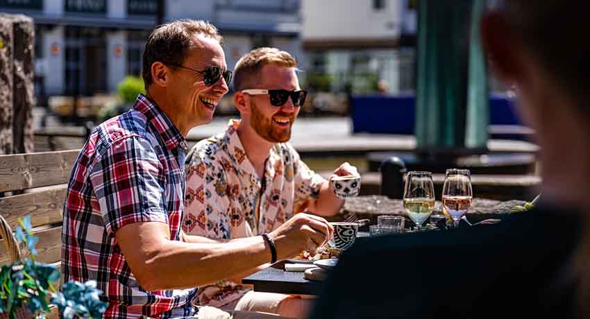 People laughing and drinking on an outdoor seating area