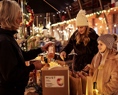 Tre personer vid ett marknadsstånd på en julmarknad i Halmstad