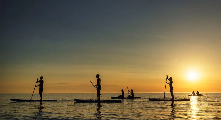 Stand upp paddle i solnedgång på havet