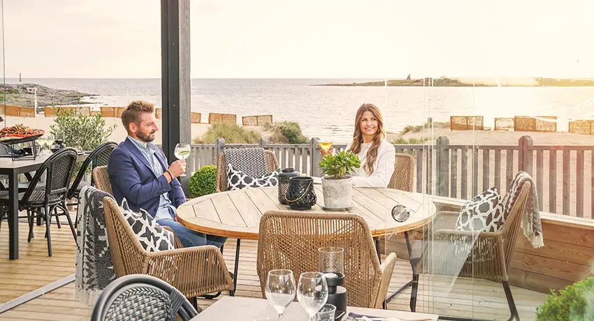  Two people are sitting on the outdoor terrace at Bettan's bar in Tylösand in Halmstad with a view of the sea.