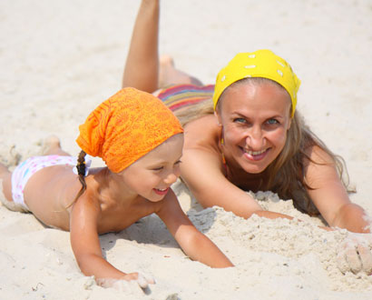 Vuxen och barn leker i sanden på en strand i Halmstad