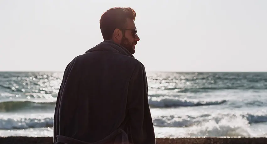  A man is standing in a bathrobe by the sea